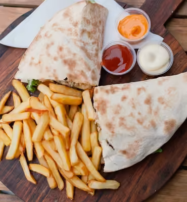 Makloub garni servi avec frites maison et sauces sur planche en bois
